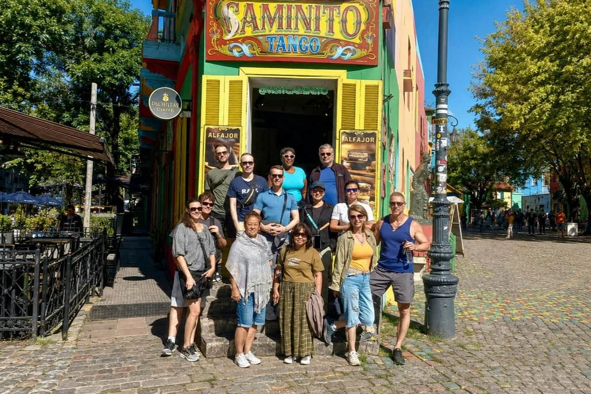 Buenos Aires: Guided Tour + Roundtrip Transfers A group of people posing in front of a colorful building labeled "Caminito Tango" on a sunny day.