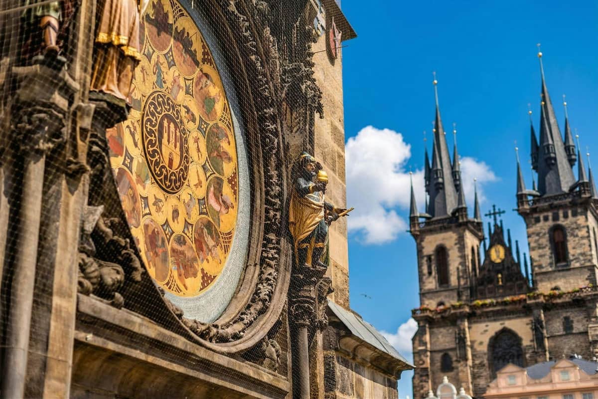 Prague : Visite de la ville à pied + Tour de l'horloge astronomique Gros plan de l'horloge astronomique de Prague avec des détails complexes et une tour d'une cathédrale gothique à l'arrière-plan.
