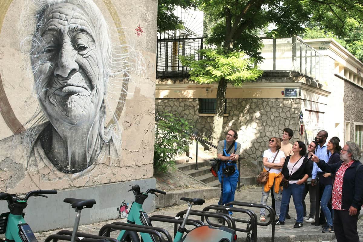 Montmartre Paris: Street Art Walking Tour Guide showing a large mural in Montmartre to a group.
