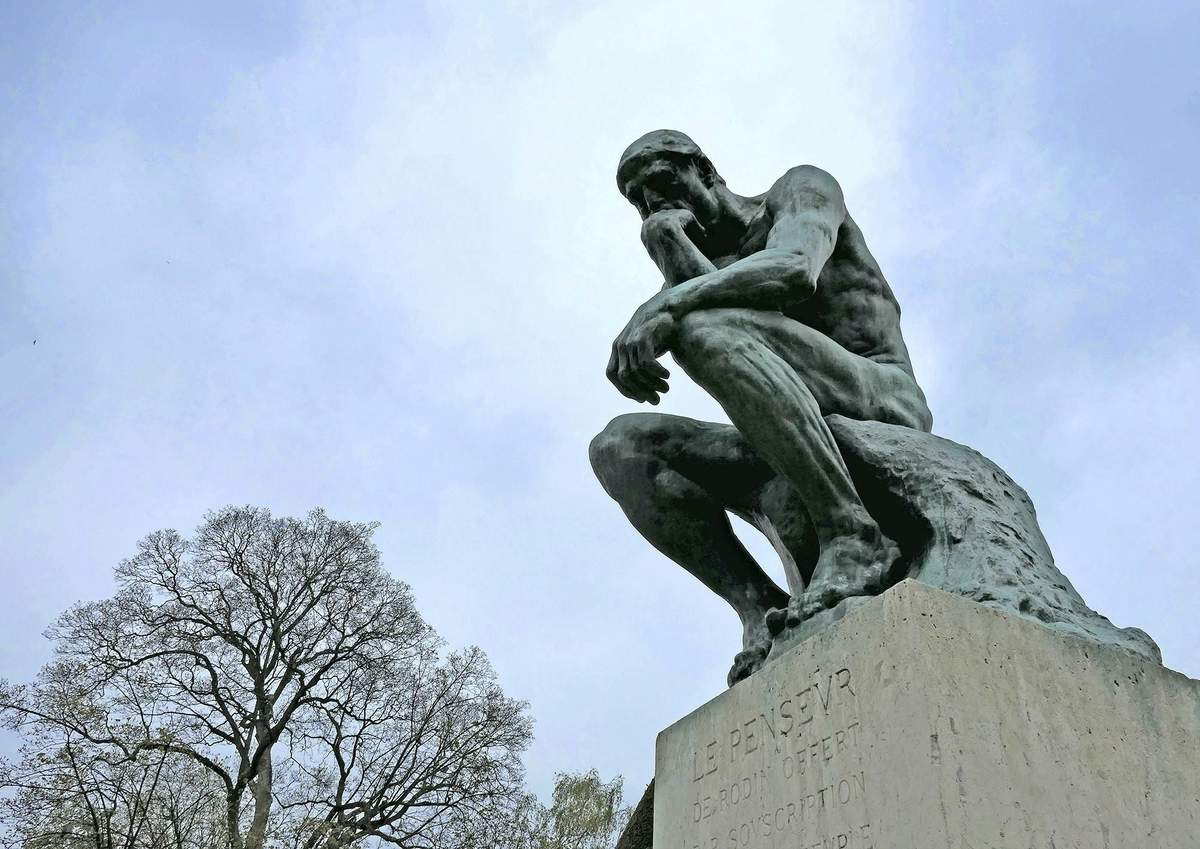Musée Rodin: Private Guided Tour Bronze statue of a man sitting and resting his chin on his hand, with trees in the background. Text "Le Penseur" visible on the base.