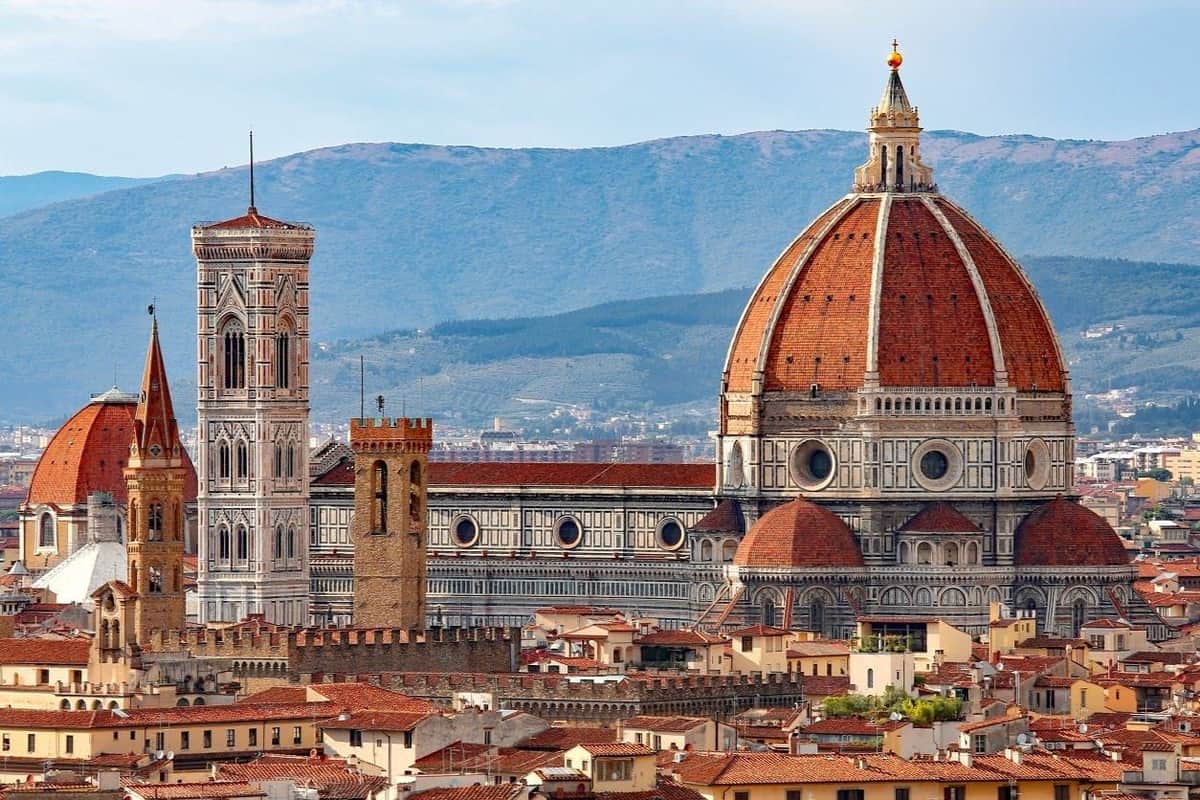 Vue panoramique de la cathédrale Santa Maria del Fiore de Florence, avec son dôme et son clocher rouges, entourée de toits.
