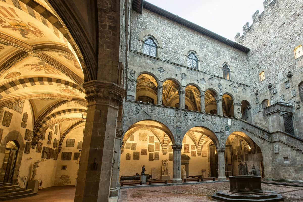 Florence: Guided City Tour + Museo Nazionale del Bargello Entry Historic courtyard with stone arches and decorative carvings, surrounded by a multi-story building with arched windows.