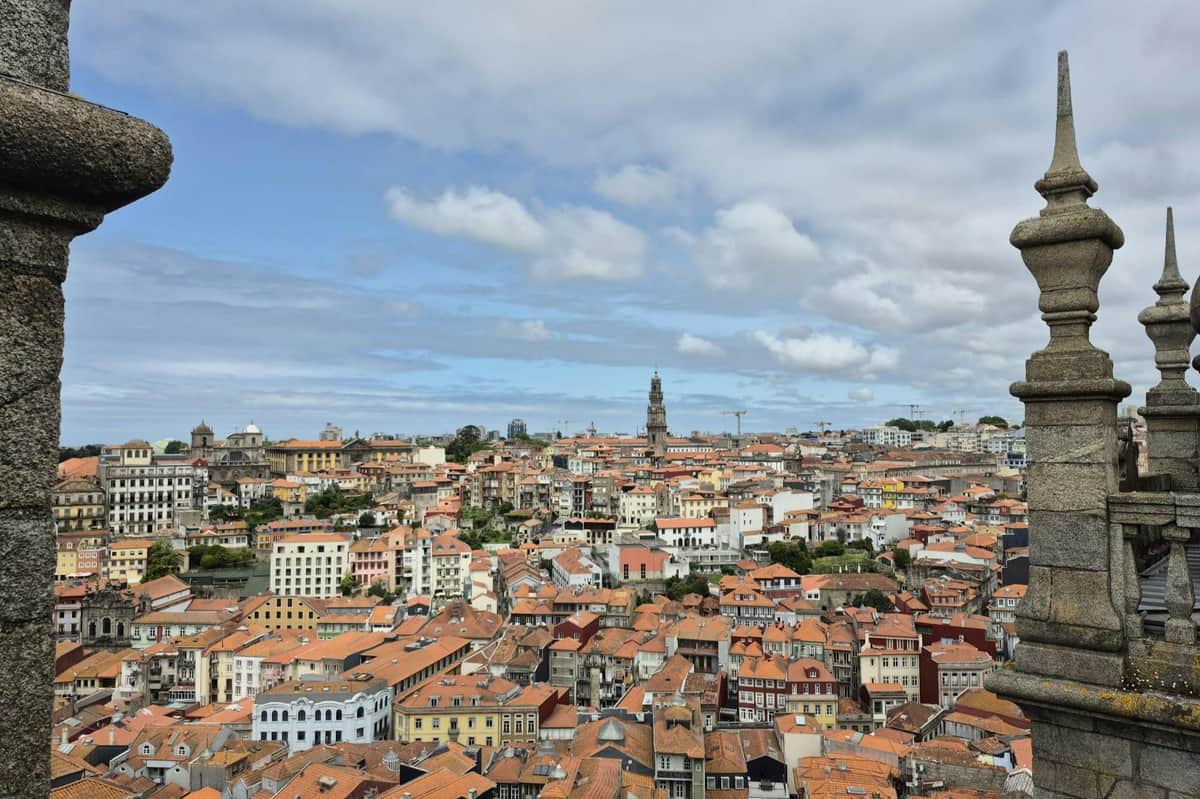 Porto: 3-Hr Guided Walking Tour (Porto) A cityscape with red-roofed buildings and a tall clock tower under a partly cloudy sky.