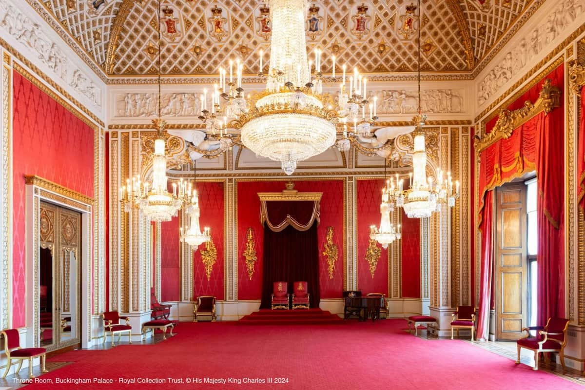 Buckingham Palace : Coupe-file + Guide audio + Visite guidée à pied de Londres Salle opulente avec des murs rouges, des lustres ornés, des accents dorés et deux chaises royales sur une plate-forme sous un dais.