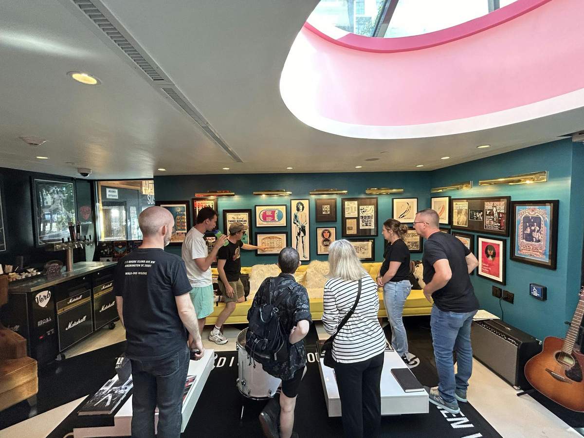 A group of people viewing framed memorabilia on the walls of a brightly lit room with a curved ceiling.