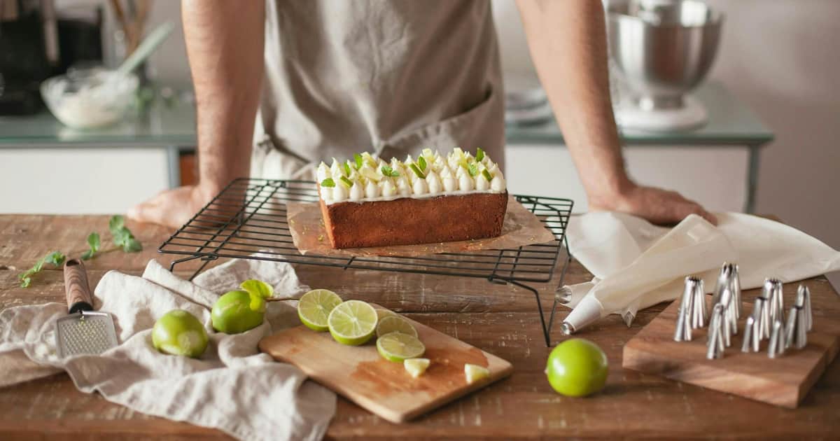 Key Lime Pie: Historic Seaport Stroll Walking Tour (Key West) A freshly decorated cake with lime slices and mint leaves on a cooling rack, surrounded by limes and a cutting board.