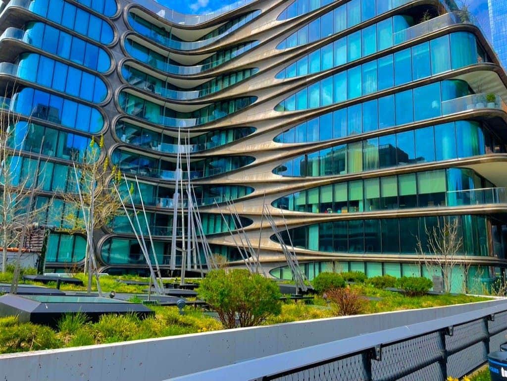 Un bâtiment moderne à l'architecture géométrique courbée, avec de grandes baies vitrées et des espaces verts au premier plan.