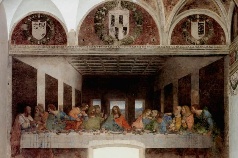 A famous mural painting depicting Jesus and his disciples seated at a long table in a large, arched room with ornate wall decorations.