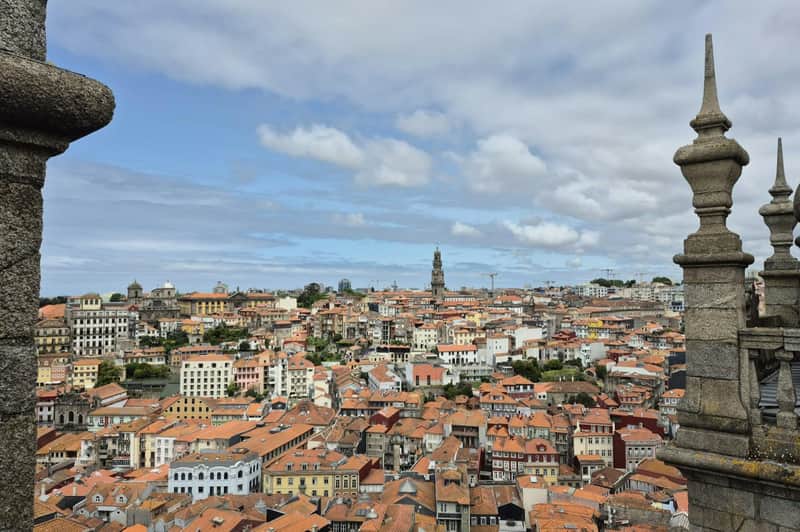 Porto: 3-Hr Guided Walking Tour (Porto) A cityscape with red-roofed buildings and a tall clock tower under a partly cloudy sky.