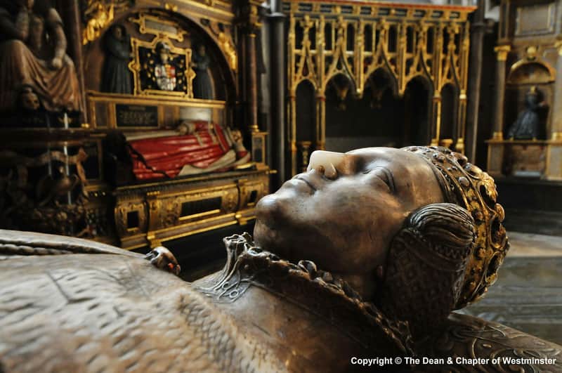 Abbaye de Westminster : Accès anticipé + Visite guidée Gros plan d'une effigie en pierre détaillée d'un personnage allongé dans un cadre médiéval, avec un arrière-plan doré et une effigie de chevalier au repos.