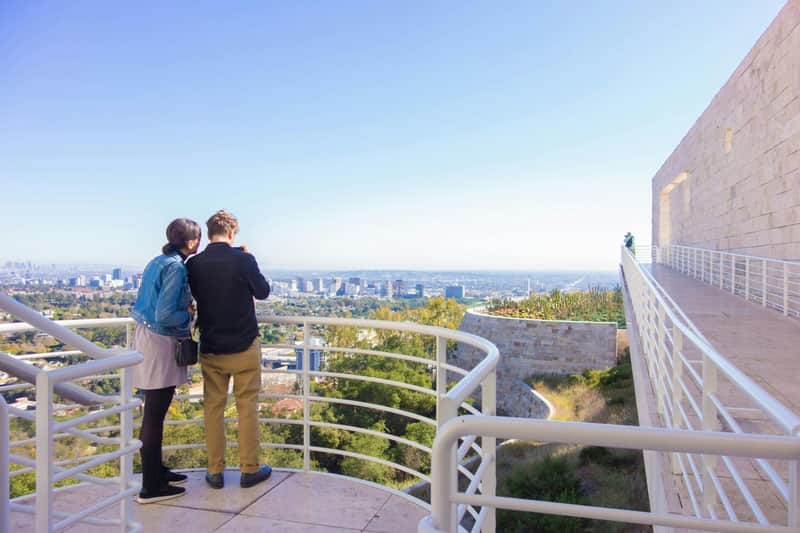 Los Angeles: The Getty Center Guided Tour (Los Angeles) Two people stand on a terrace overlooking a cityscape, with railing and a clear blue sky in the background.